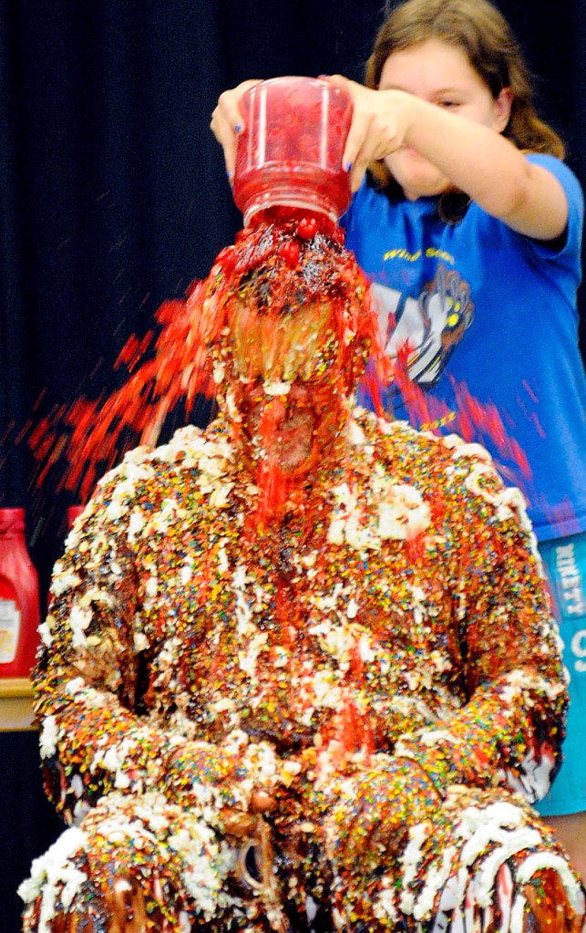 Windsor Elementary School fourth-grader Sydni Plummer dumps cherries on the head of principal Rob Moody on Tuesday, during a celebration at the school in which students and faculty turned Moody into a human sundae. Moody challenged students to at the beginning of the school year to read 170 million words and master 8,000 math objectives; children enrolled in the K-8 grades exceeded that amount by reaching 188 million words and learning 10,250 math objectives, Moody said. Plummer was recognized for reading over 12 million words.