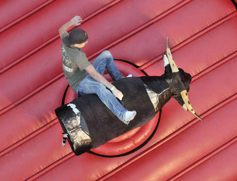 Caleb Patten, 15, tests his strength on the mechanical bull at the East Coast Midways carnival in Fairfield on Thursday.