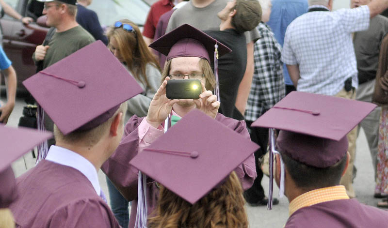 Jackson Pendleton, facing center, takes photos of friends before Nokomis High School's commencement ceremonies in Newport on Friday.