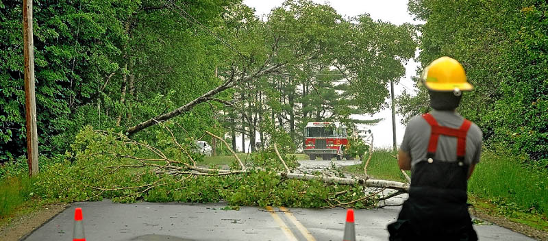 Lloyd Cole, right, with the Madison Fire Department stands by a closed section of Russell Road in Madison on Tuesday, after a thunderstorm knocked down trees and power lines.