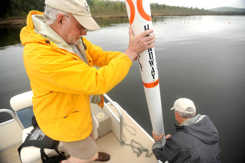 Gordon Wood, left, and Rob Jones install a speed limit buoy Friday morning at both ends of the Serpentine, a three-mile-long narrow stretch of shallow water that connects East Pond with North Pond, in an effort to slow boaters and personal watercraft operators. The buoys are part of the the LakeSmart program that is currently implemented on East Pond.