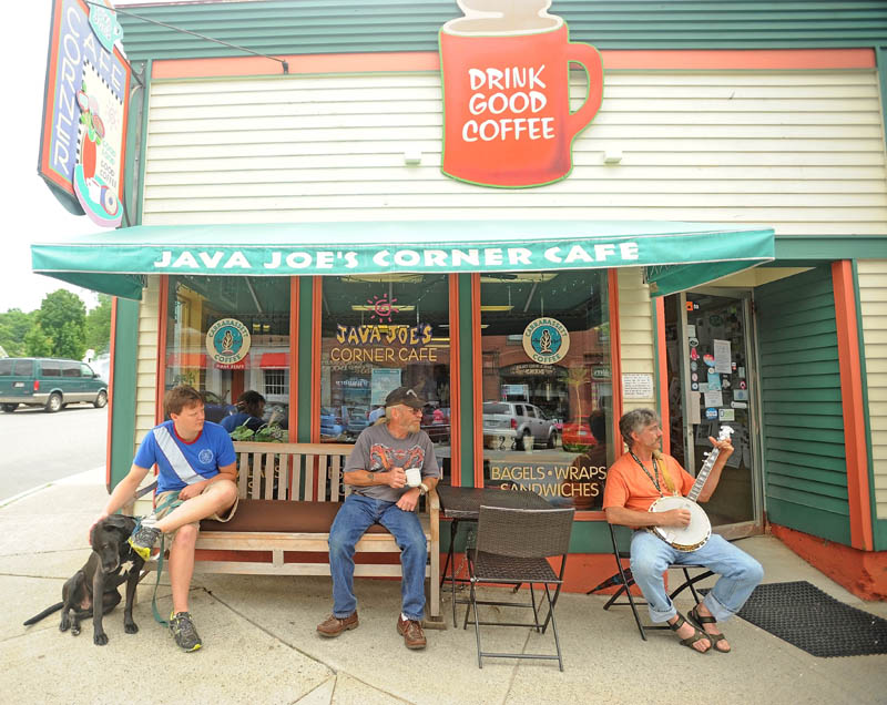 Pep Stevens, 52, right, picks his banjo outside Java Joe's Corner Cafe as Jay Heyse, center, and Zach Lopez, left, listen over a cup of coffee at the first Summer Solstice Celebration in downtown Farmington on Saturday.