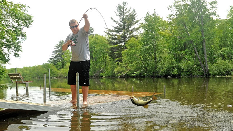 Ben Misner, 16, hauls in a largemouth bass from the dock on the Messalonskee Stream on North Street in Waterville on Thursday.