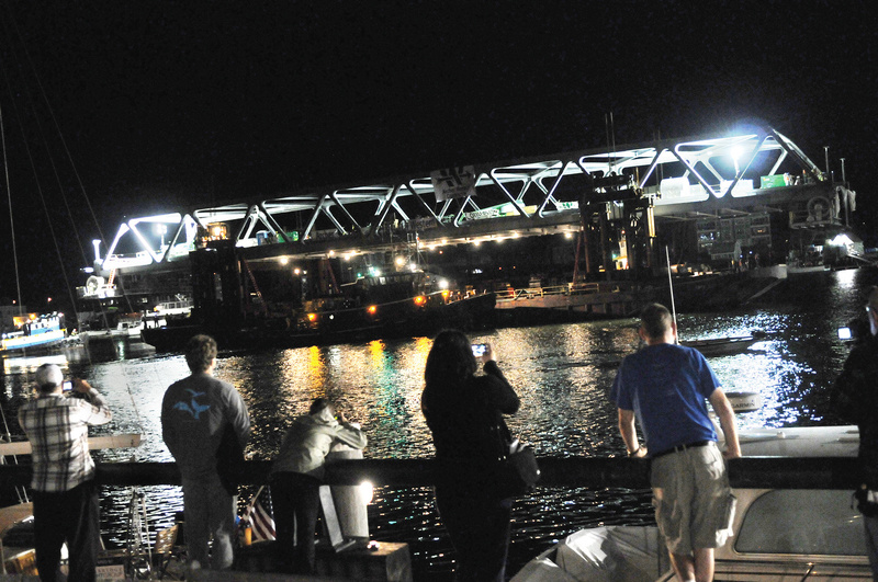 Spectators gather as the final span of the new Memorial Bridge connecting New Hampshire and Maine floats down the Piscataqua River early Monday in Portsmouth, N.H. River traffic won't be allowed for five days as the bridge is hooked up and tested.
