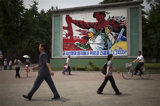 People walk past a roadside propaganda billboard promoting the "military first" policy and a boost to build the country's economy in Pyongyang, North Korea, on Sunday.