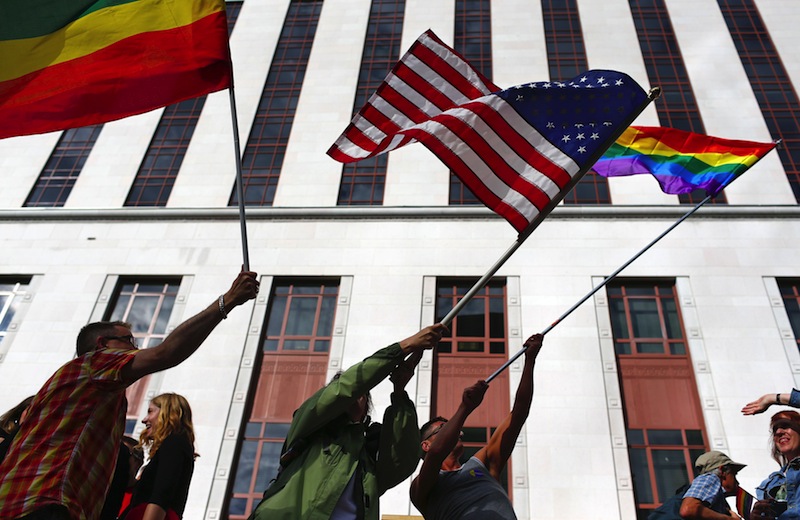 People wave American and gay pride flags outside the old Federal Courthouse in downtown Seattle on Wednesday, June 26, 2013, to celebrate the striking down of the Defense of Marriage Act by the Supreme Court. (AP Photo/The Seattle Times, John Lok)