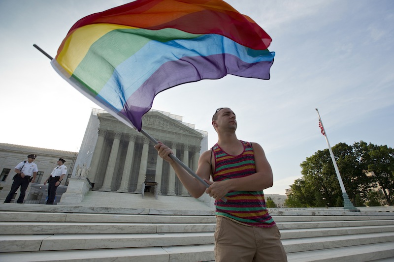 Gay rights advocate Vin Testa waves a rainbow flag in front of the Supreme Court at sun up in Washington, Wednesday, June 26, 2013. In two separate and significant victories for gay rights, the Supreme Court struck down a provision of a federal law denying federal benefits to married gay couples and cleared the way for the resumption of same-sex marriage in California. (AP Photo/J. Scott Applewhite)