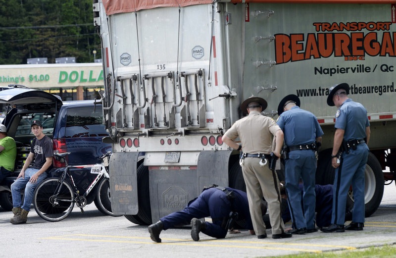The driver of the tractor-trailer, left, who the police believe was involved in the fatal accident in Hanover, looks on as his truck is inspected by police in Rumford on Friday, June 14, 2013. The bike involved in the collision is leaning against the vehicle.