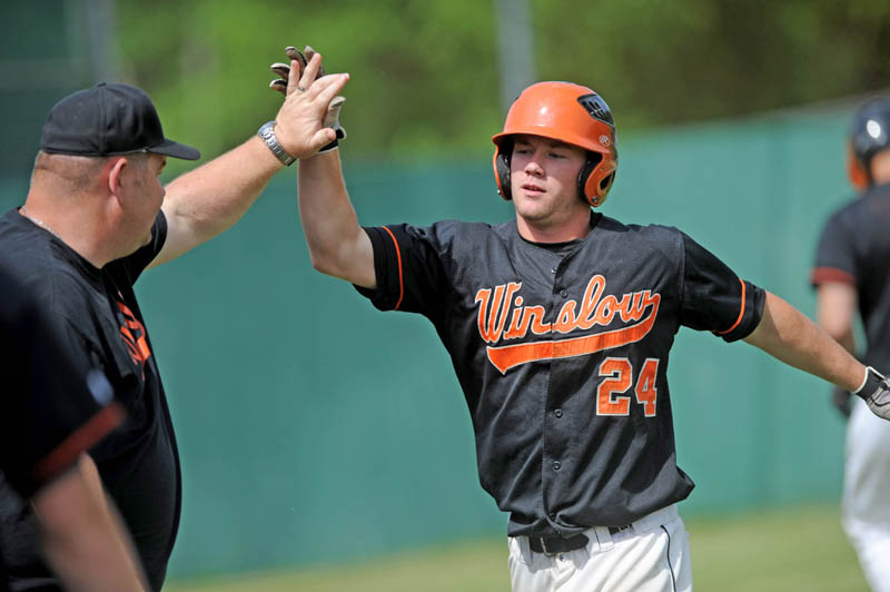 ON THE BOARD: Winslow High School’s Dylan Hapworth, right, gets a high five from an assistant coach after crossing the plate for a run in the first inning of the Black Raiders’ 7-0 win over Washington Academy in an Eastern B quarterfinal game Thursday in Winslow.