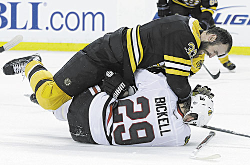 BRING IT: Boston defenseman Zdeno Chara (33), takes down Chicago left wing Bryan Bickell during the third period in Game 3 of the Stanley Cup finals Monday in Boston.