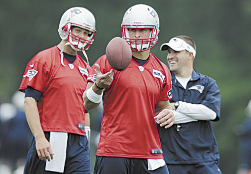 NEW IN TOWN: New England Patriots quarterback Tim Tebow, center, tosses the ball as Tom Brady, left, talks with offensive coordinator Josh McDaniels during practice Tuesday in Foxborough, Mass.