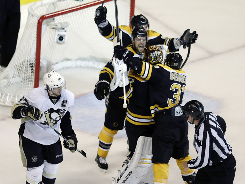 BIG-TIME WIN: Boston’s Patrice Bergeron embraces goalie Tuukka Rask as Pittsburgh Penguins center Sidney Crosby (87) skates away after the Bruins won Game 4 of the Eastern Conference finals Friday night in Boston. The Bruins swept the series, 4-0, to advance to the Stanley Cup finals.
