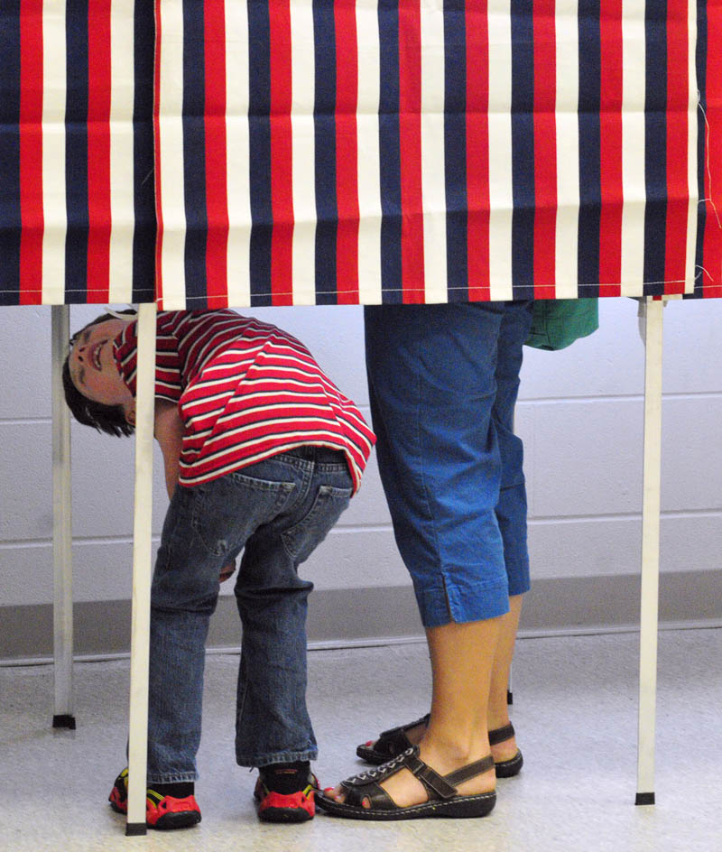 Samuel Goldey, 7, looks up at his mother, Anya Goldey, while she casts a ballot on Tuesday at the Ward 4 polling place in the Cony Middle School music room in Augusta.