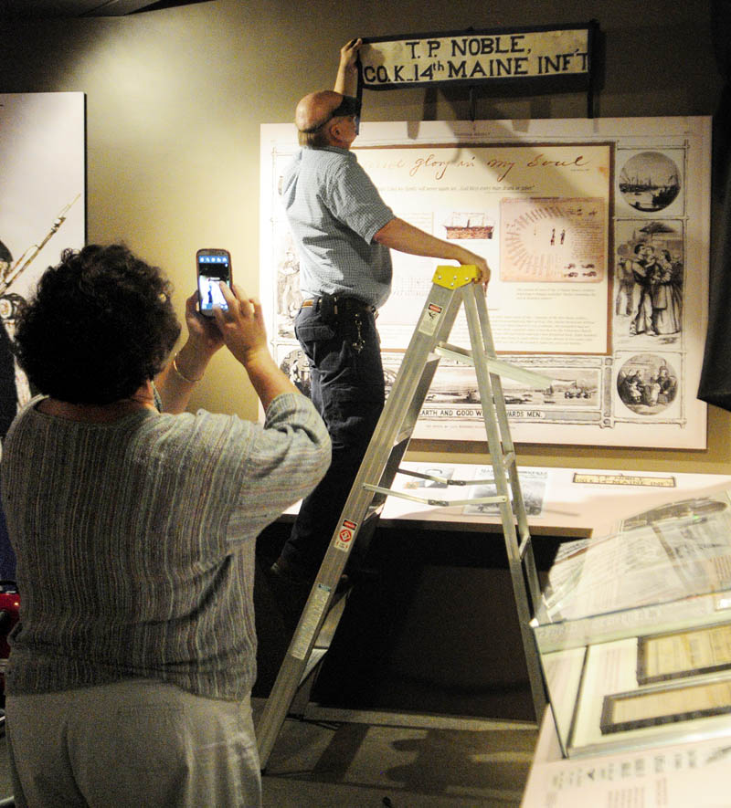 Curator Laurie LaBar, left, takes a photo of where graphic artist Don Bassett is positioning a banner for the exhibit titled "Maine Voices from the Civil War," on Wednesday at the Maine State Museum in Augusta.
