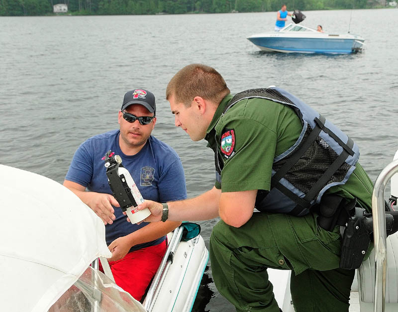 Deputy Game Warden Harry Wiegman checks the fire extinguisher on Steve Sirios' boat while doing a safety check on Wednesday on Messalonskee Lake.