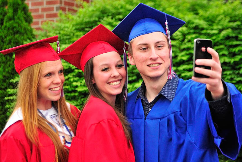 Emily Deering, left, Zoe Nielsen and Andrew Knoedler pose for a shot with his smart phone before Messalonskee graduation on Thursday at the Augusta Civic Center.
