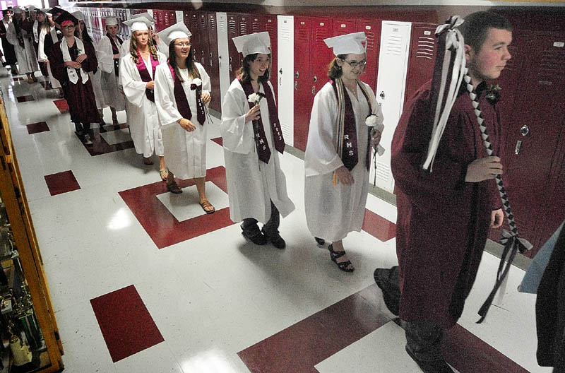 Marshal Skyler Mayers, far right, leads a line of maroon- and white-clad seniors down a maroon-and-white hallway, on their way into the gym for their commencement ceremony on Saturday at Richmond High School.