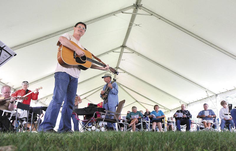 Mike Robinson, of Belchertown, Mass. leads in the singing some hymns under the big tent on Sunday morning at the 40th Blistered Fingers Bluegrass Festival at the Litchfield Fairgrounds. Robinson and his wife, Mary, not shown, travel the country to bluegrass festivals to share the gospel both in word and in song.