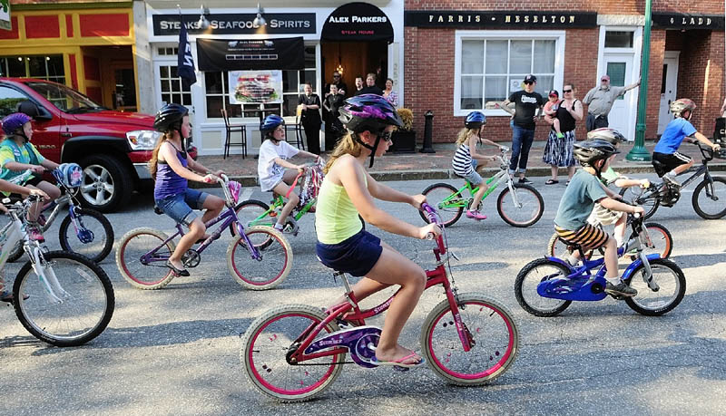 Children ride bicycles down Water Street on Saturday in downtown Gardiner as part of the 4th annual Ride into Summer. The event included a motorcycle ride around town, peoples' choice pizza contest of local traditional and non-traditional pizzas, live music, and was capped off with a fireworks display along the Kennebec River.
