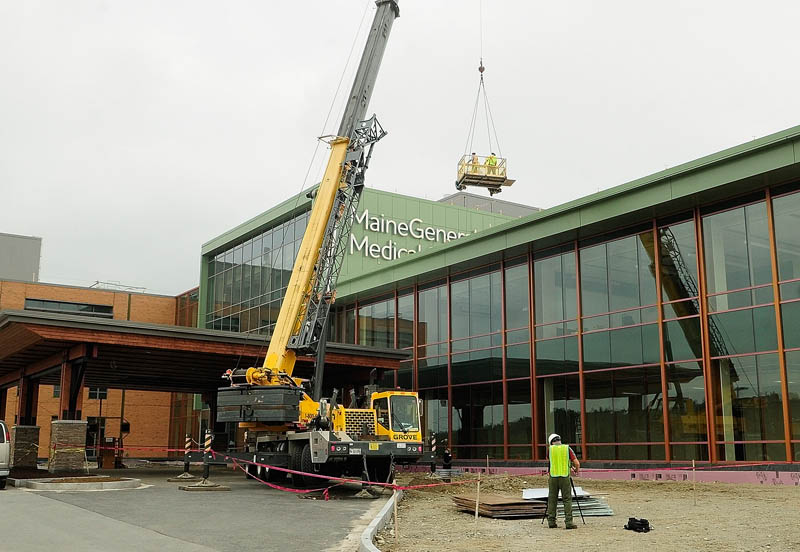 A crane lifts workers up to clean the walls around the recently mounted sign letters on top of the Alfond Center for Health regional hospital, to be operated by MaineGeneral Health, on Wednesday in Augusta.