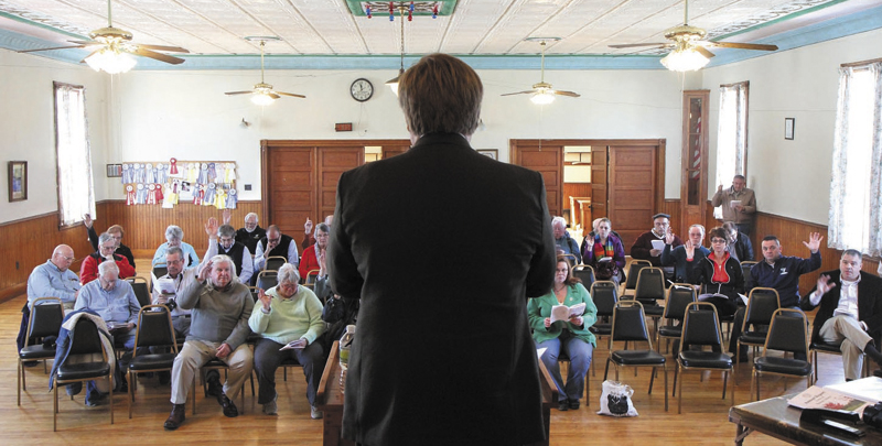 Residents vote on an article as moderator David Benier presides over the annual Benton Town Meeting inside the Benton Grange Hall recently.