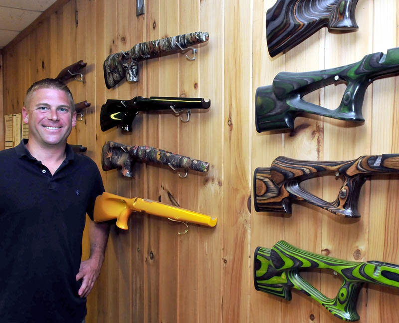 Cousineau Wood Products Vice President Brody Cousineau on Monday stands next to some of the wood veneer gun stocks made at the North Anson company.