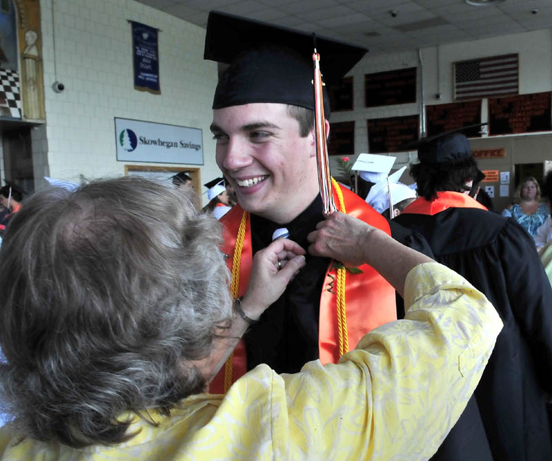 Skowhegan Area High School graduate Cory Palmer smiles as Eleanor McClay struggles to pin a corsage on him prior to commencement on Sunday.