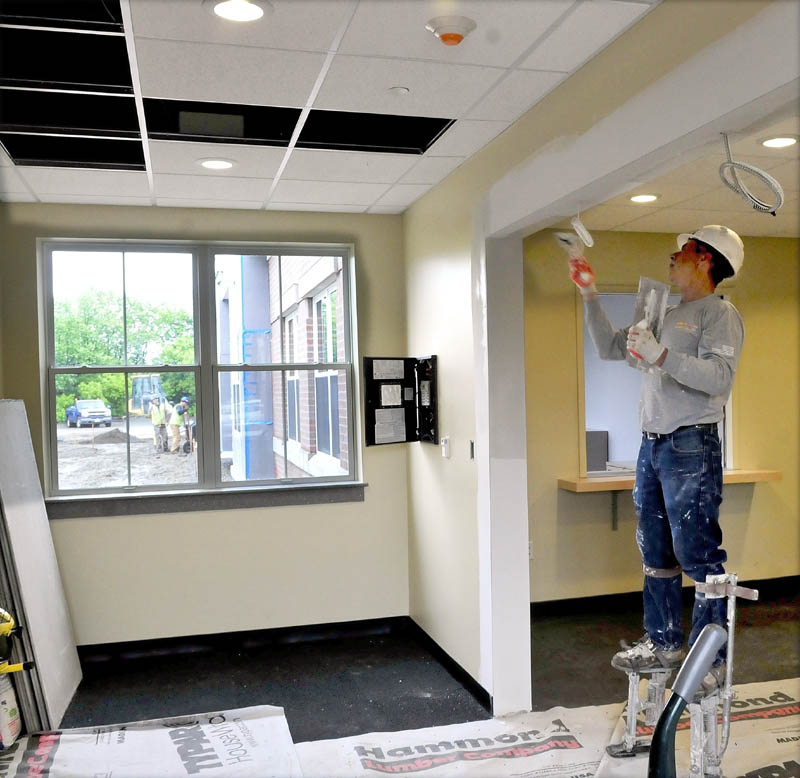 Dan Poirier tapes the ceiling at the entrance to the new Waterville police station on Wednesday.