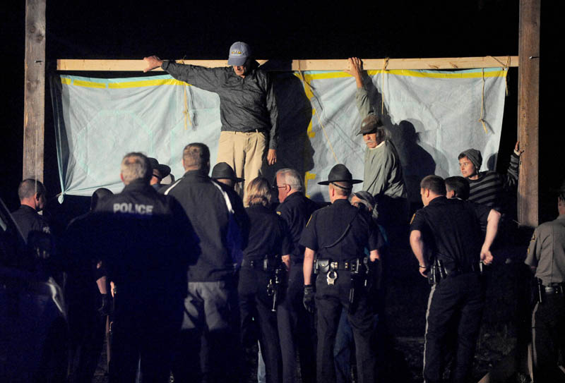 Authorities approach members of 350 Maine atop a scaffold that blocked the railroad crossing at Lawrence Avenue in Fairfield Thursday night, to protest the transport of fracked oil on the line.