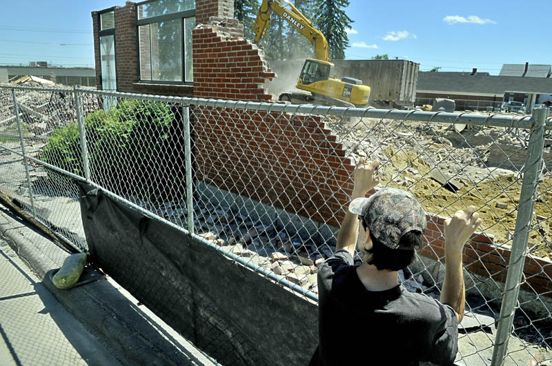 Jon Duffy watches as the final pieces of St. Francis de Sales Church in Waterville are brought down Wednesday. He said he gathered there with others to witness the passing of the old church. Several reasons including high maintenance costs led to the demolition of the church, which was finished in 1874. A three-story housing complex will go up at the site and is expected to be completed in June 2014.