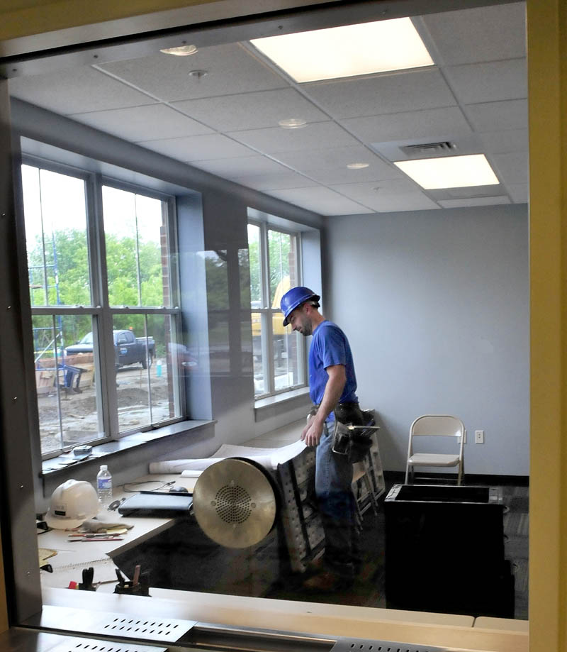 Construction worker Ian Deforge looks over building plans inside the dispatch room in the new Waterville Police Department station on Wednesday.