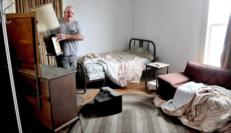 Marc Wheeler removes a brass lamp that will be salvaged, after other items are disposed of, from a room on the second floor of the former Kennebec Valley Inn in Skowhegan, on Tuesday. Wheeler and his wife, Janet, plan to open the Blue Moon Lounge this summer and renovate sections of the building for future banquet events.