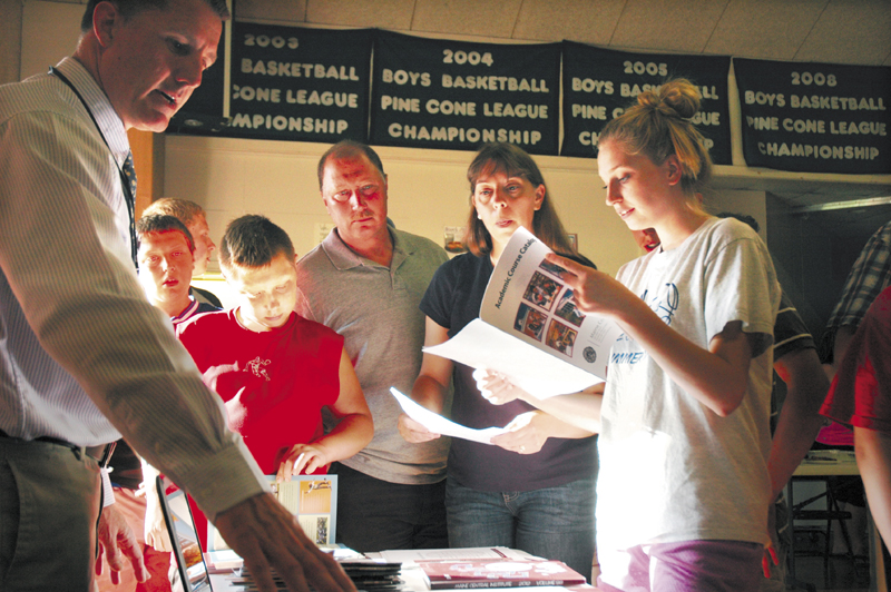 Mona Bussell, 16, right, browses through an academic catalog for Maine Central Institute, along with her parents, Cory and Jean Bussell, as they speak with Dean of Admissions Clint Williams, left. MCI was one of seven schools at a high school fair in Athens Monday evening.