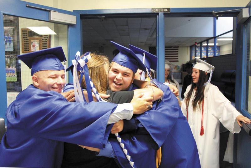 Anthony Giresi, center, and Tyler Lafreniere, left, give former math and science teacher Kim McEwen a hug before commencement exercises at Madison Area Memorial High School on Friday night. McEwen now teaches at Skowhegan Area High School and said she wanted to be there to see her former students graduate.