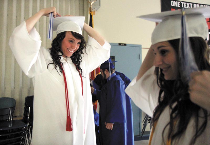 Courtney Taylor, left, looks over at Alexander McClintock, right, as they adjust their caps before the start of commencement exercises at Madison Area Memorial High School on Friday night.