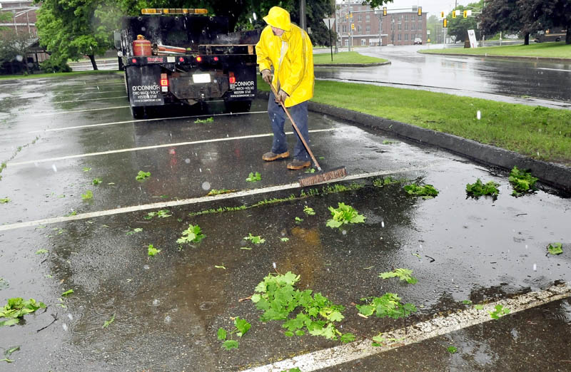 Bobbie Bellows of the Waterville public works department sweeps leaves and branches after trimming trees overhanging Front Street on a wet Tuesday.