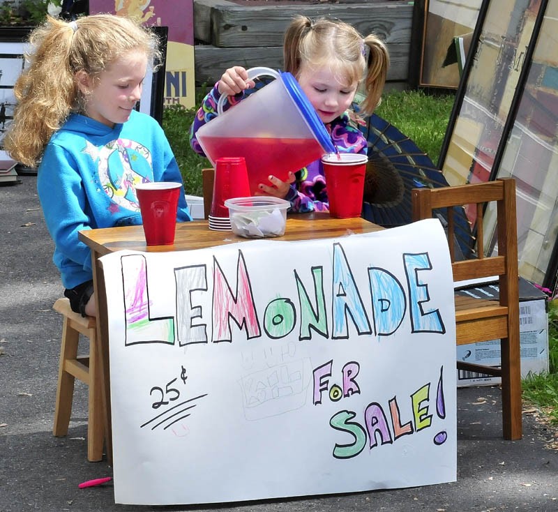 Briana Veilleux, left, and Kenadie Dickey fill cups with lemonade at their stand in Waterville on Sunday, The girls said that sales were steady enough to require a second pitcher.
