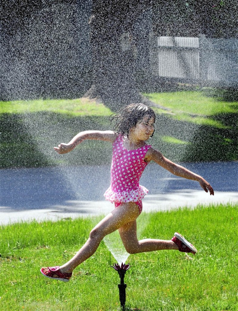 The hot weather brought out a sprinkler for Emiko Peck, seen running through the water to cool off, at her home in Waterville on a hot and muggy Sunday. Emiko and her sister, Mimako, ran from sprinkler to kiddie pool to ward of the heat.