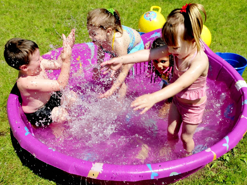 Children take a dip in a kiddie pool to cool off and have fun, in Skowhegan on Wednesday. From left are Gabe Dougherty, Kaydance Poulin, Raelynn Poulin and Rowen Rogers.
