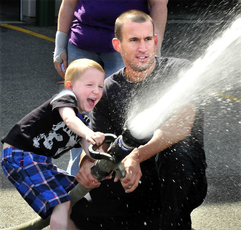 James Rackliff, a kindergarten student at the George Mitchell School, reacts with joy as he and Waterville firefighter Pablo Passalacqua turn on a water hose at Central Station on Monday. The class visited the station as part of a field day before heading to the city library.