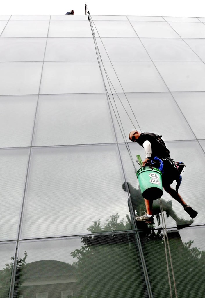 Jerry Croci rappels down a huge wall of glass panes on the new Colby College Museum of Art in Waterville, while washing the glass on Monday. Sixty feet above Croci was Jay Schaible, who moved Croci's rope harness equipment sideways as needed.