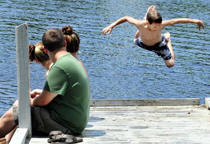 As teenagers watch, Jonathan Rogers does a backward flying leap off the dock and into the Kennebec River at the boat landing in Madison on a hot Monday.