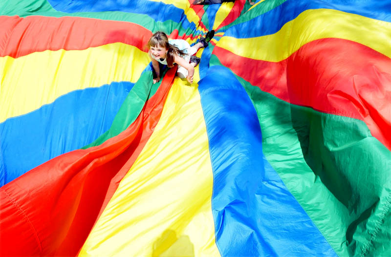 Fairfield Primary School student Kelsey Rideout tries to get to the outside of a colorful parachute as classmates flip up the sides during an end-of-school-year field day on Monday.