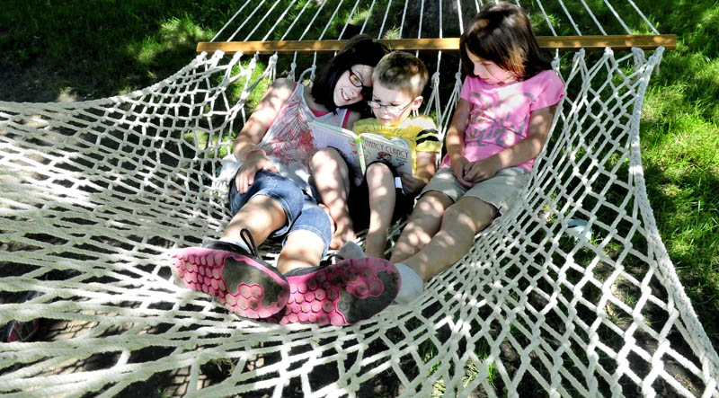 The McAlpine children beat the heat by grabbing a book and reading on a hammock in the shade at their home in Waterville on Monda. From left are Jenna, Iain and Audrey.