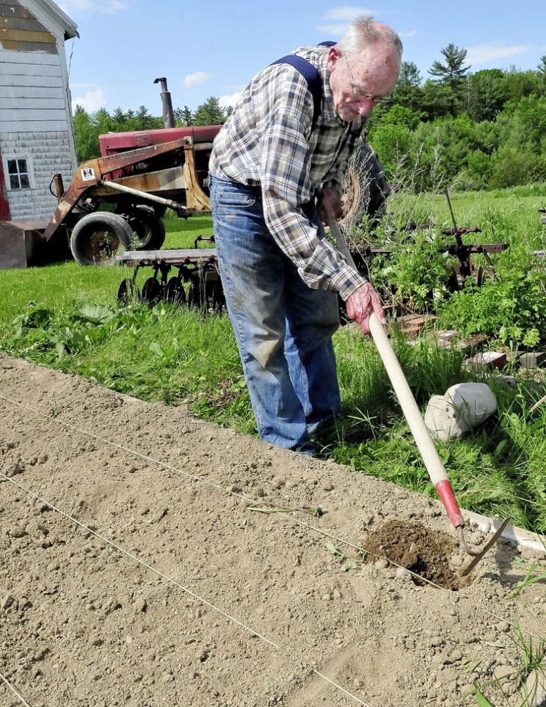 Merton Webber works the soil in one of his raised garden beds at his farm in Winslow on Tuesday. Webber, 90, has gardened and farmed for most of his life, he said.