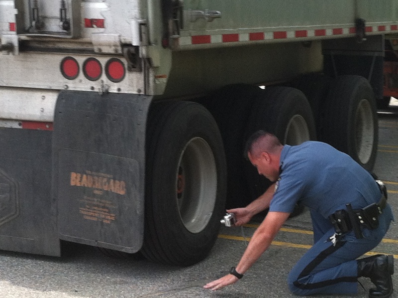 Maine State Police Trooper Joe Bureau inspects the rear tire of a Canadian truck police suspect was involved in Friday's fatal bicycle accident in Hanover.