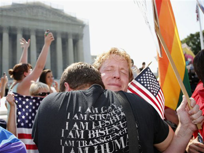 Michael Knaapen, left, and his husband John Becker, right, embrace outside the Supreme Court in Washington on Wednesday after the court struck down a federal provision denying benefits to legally married gay couples.