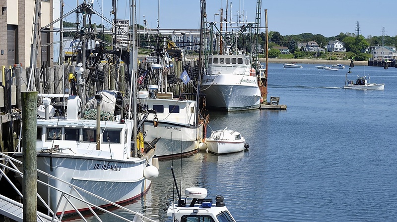 A lobster boat passes by fishing boats in Portland.
