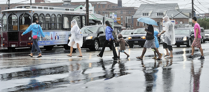 Tourists dressed in a variety of rain gear cross Commercial Street on Monday as rain falls at the beginning of the Fourth of July week.