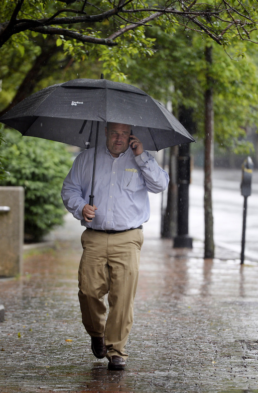 Todd Zukowski of Portland takes cover under an umbrella while walking along Temple Street in Portland during Monday's rain.